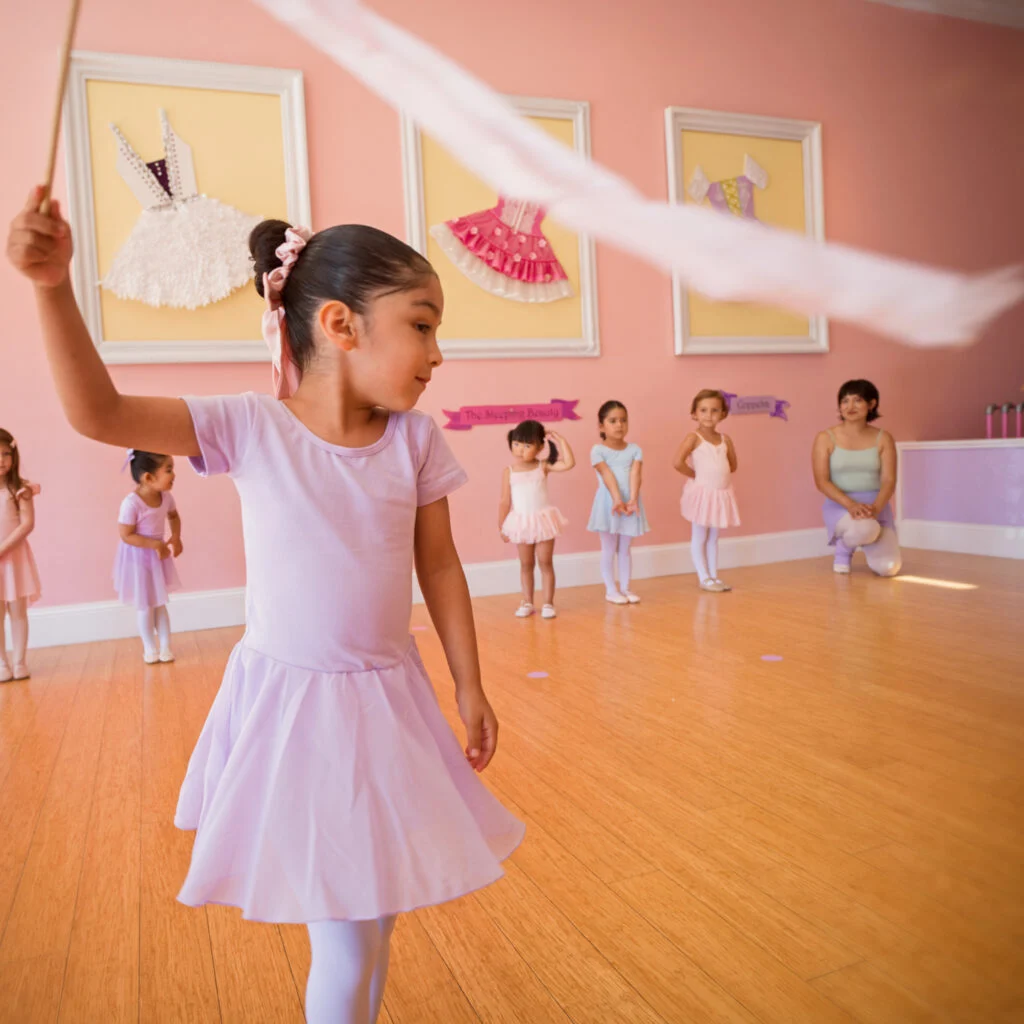 Children in ballet class at tutu school dancing with ribbons
